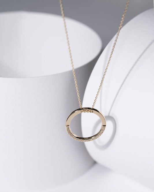 circle karma necklce in 14k gold half of the necklace is paved with cubic zirconia stones