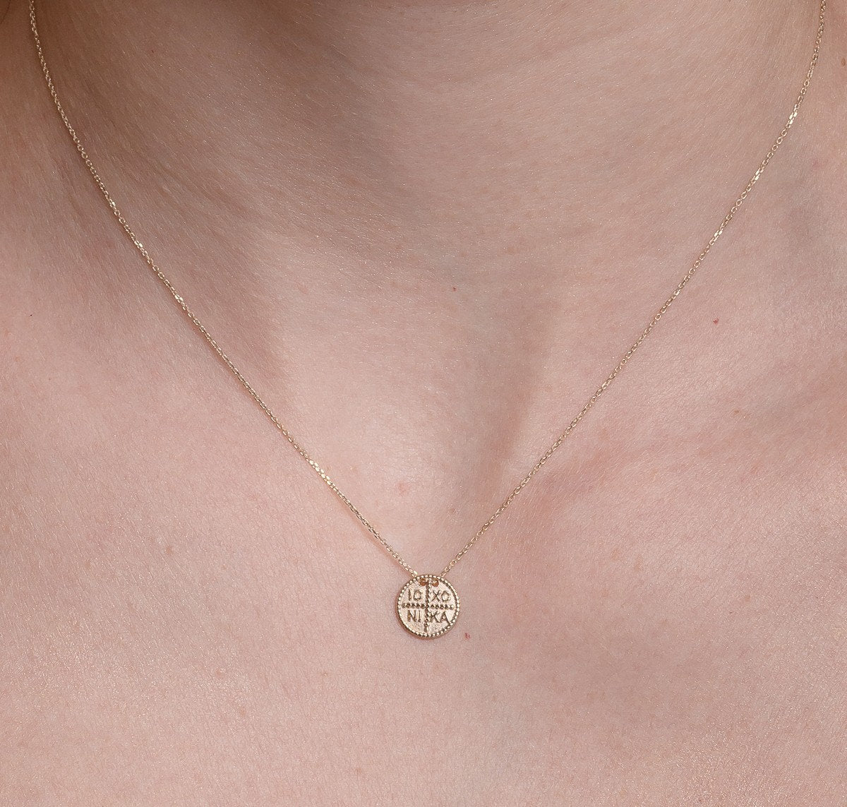 christian coin necklace in 14k yellow gold for women worn by a model 