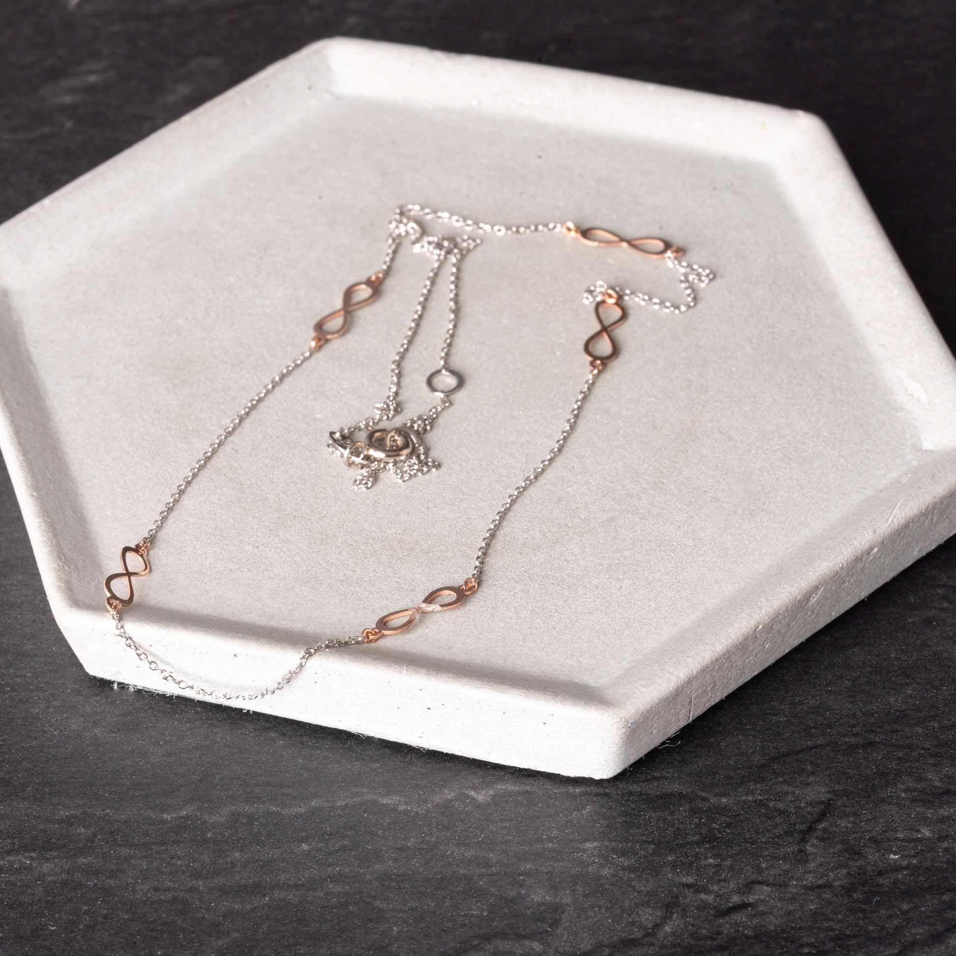 A station necklace featuring five infinity symbols in rose gold, complemented by a chain in white gold.