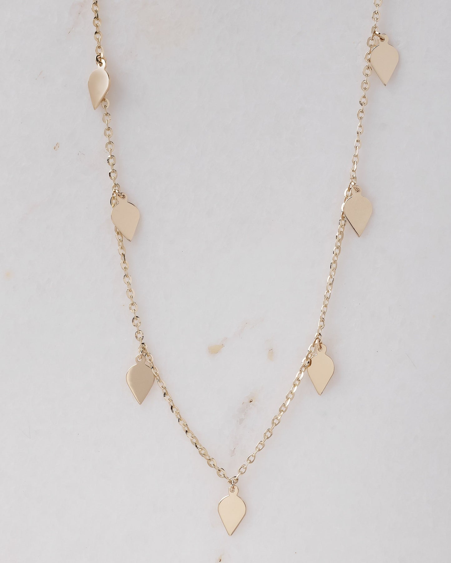 A station necklace featuring seven leaves crafted in 14k yellow gold for women.