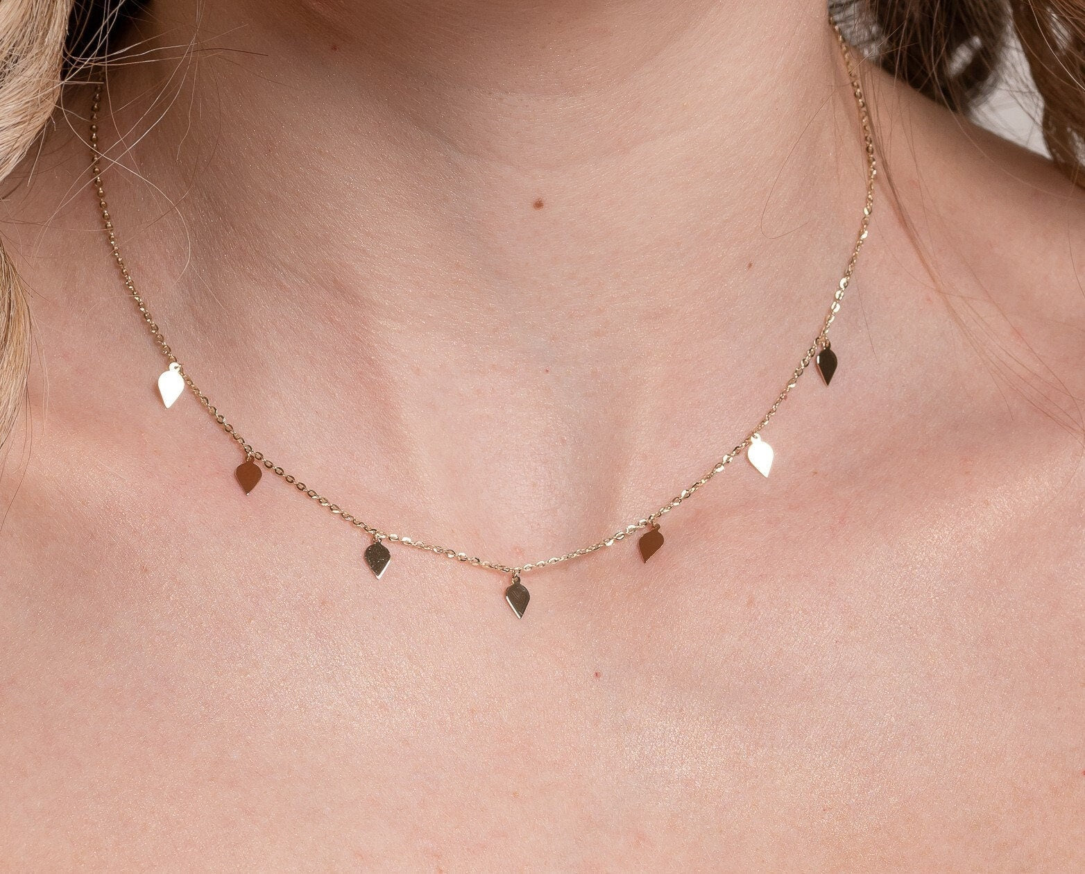 A station necklace featuring seven leaves crafted in 14k yellow gold for women.