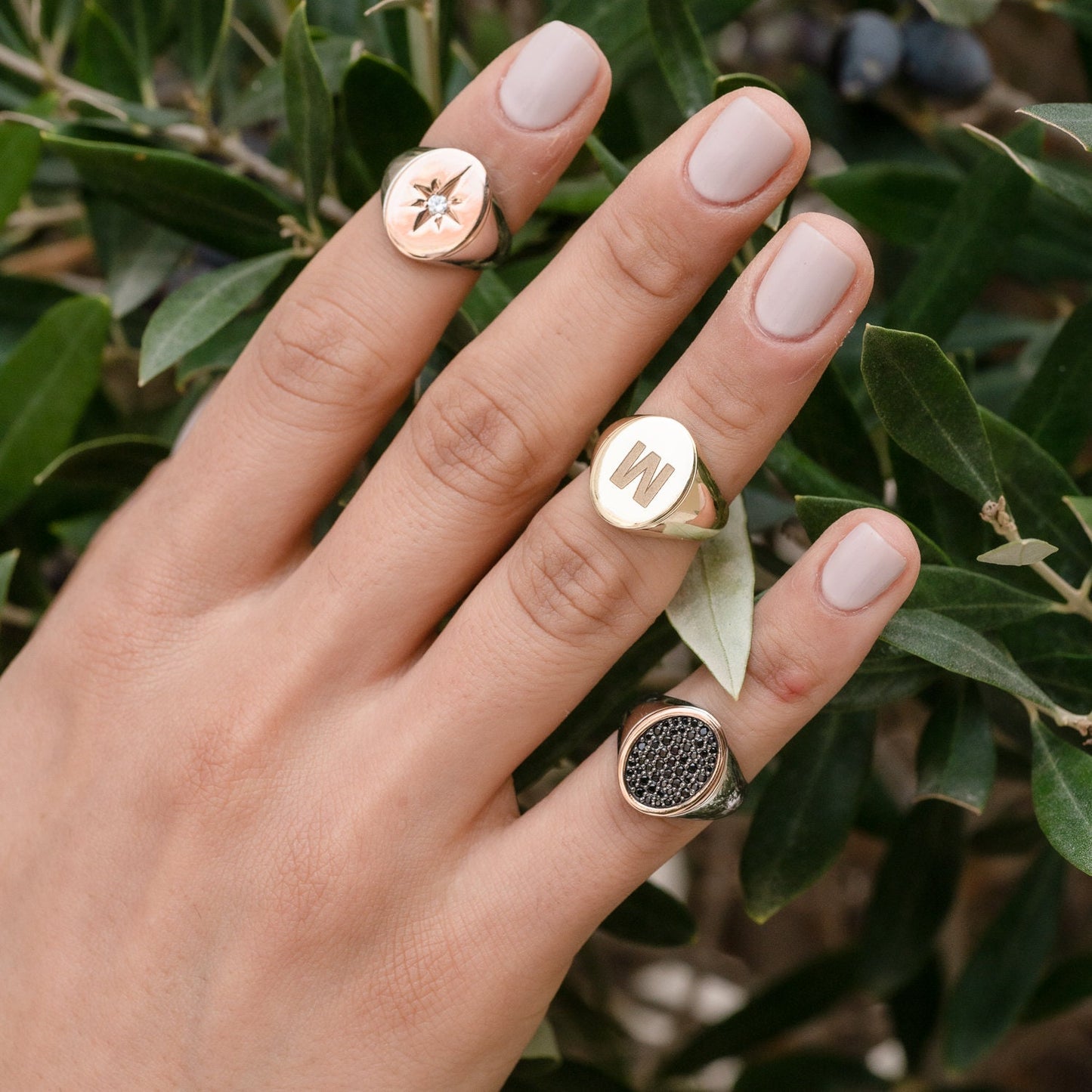 stylish collection of signet rings, featuring various designs worn by a model