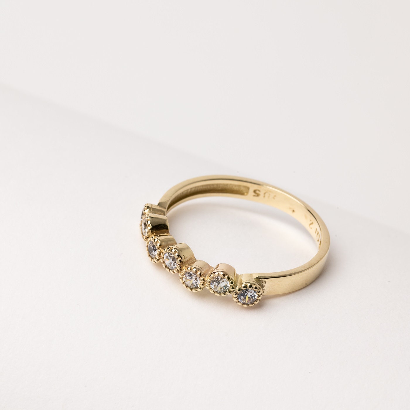 A half-eternity asymmetrical band crafted in 14k solid gold, adorned with white cubic zirconia stones.