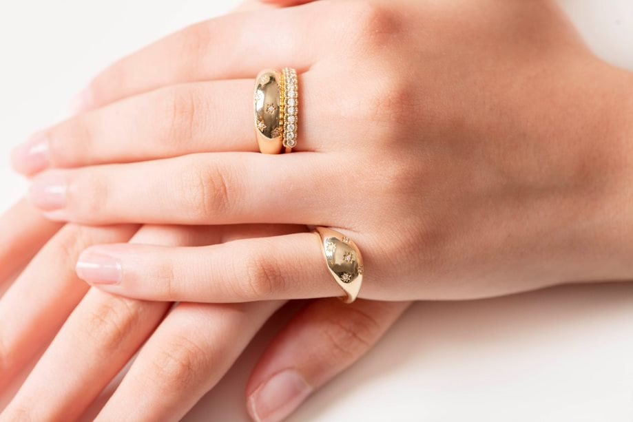 Two dome rings adorned with stars and a half-eternity band, showcased by a model.