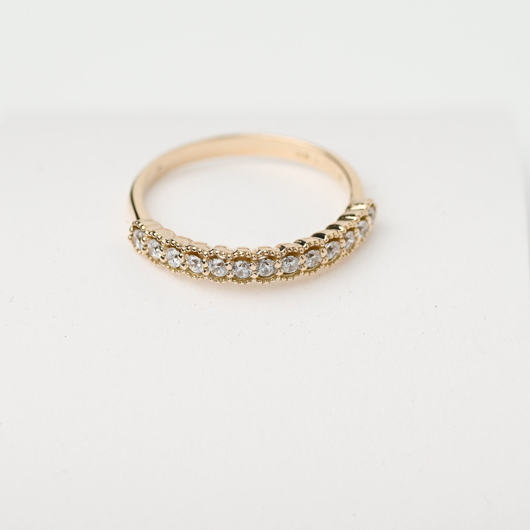 A women's half-eternity band ring featuring white cubic zirconia stones set in 14k gold.