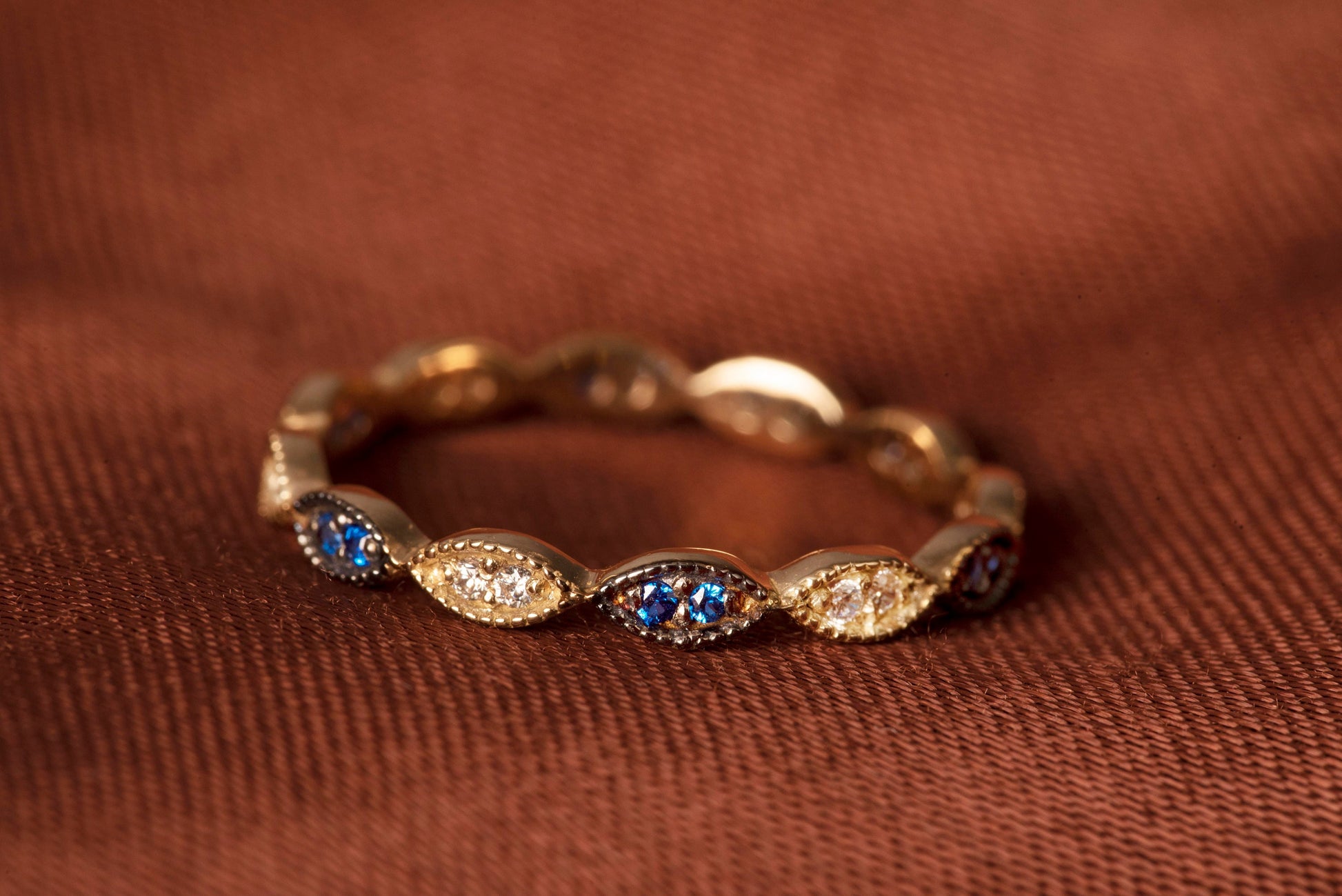 A full eternity band ring crafted in 14k gold, adorned with white and blue cubic zirconia stones.