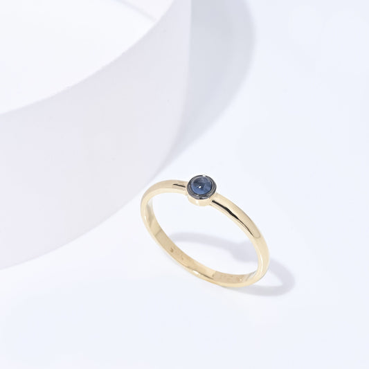 A handmade ring featuring a single birthstone in a bezel setting, crafted in 14k gold for women.