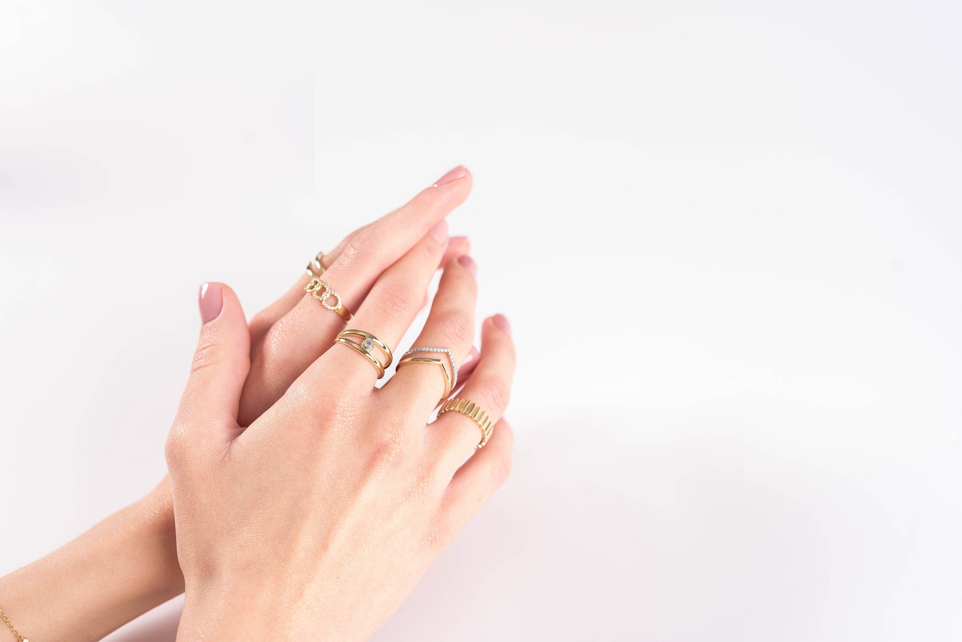 This image features hands adorned with delicate gold rings, showcasing a variety of styles including gemstone accents, twisted bands, and minimalist designs.