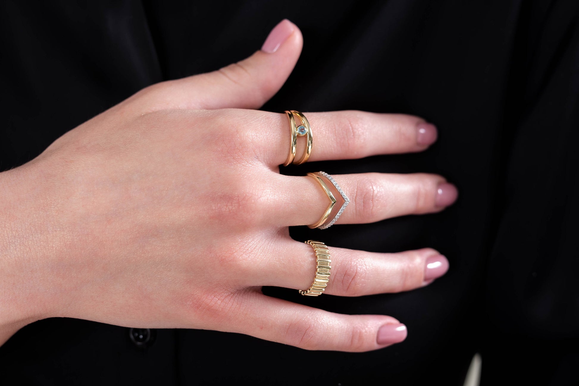 This image features hands adorned with delicate gold rings, showcasing a variety of styles including gemstone accents, twisted bands, and minimalist designs.