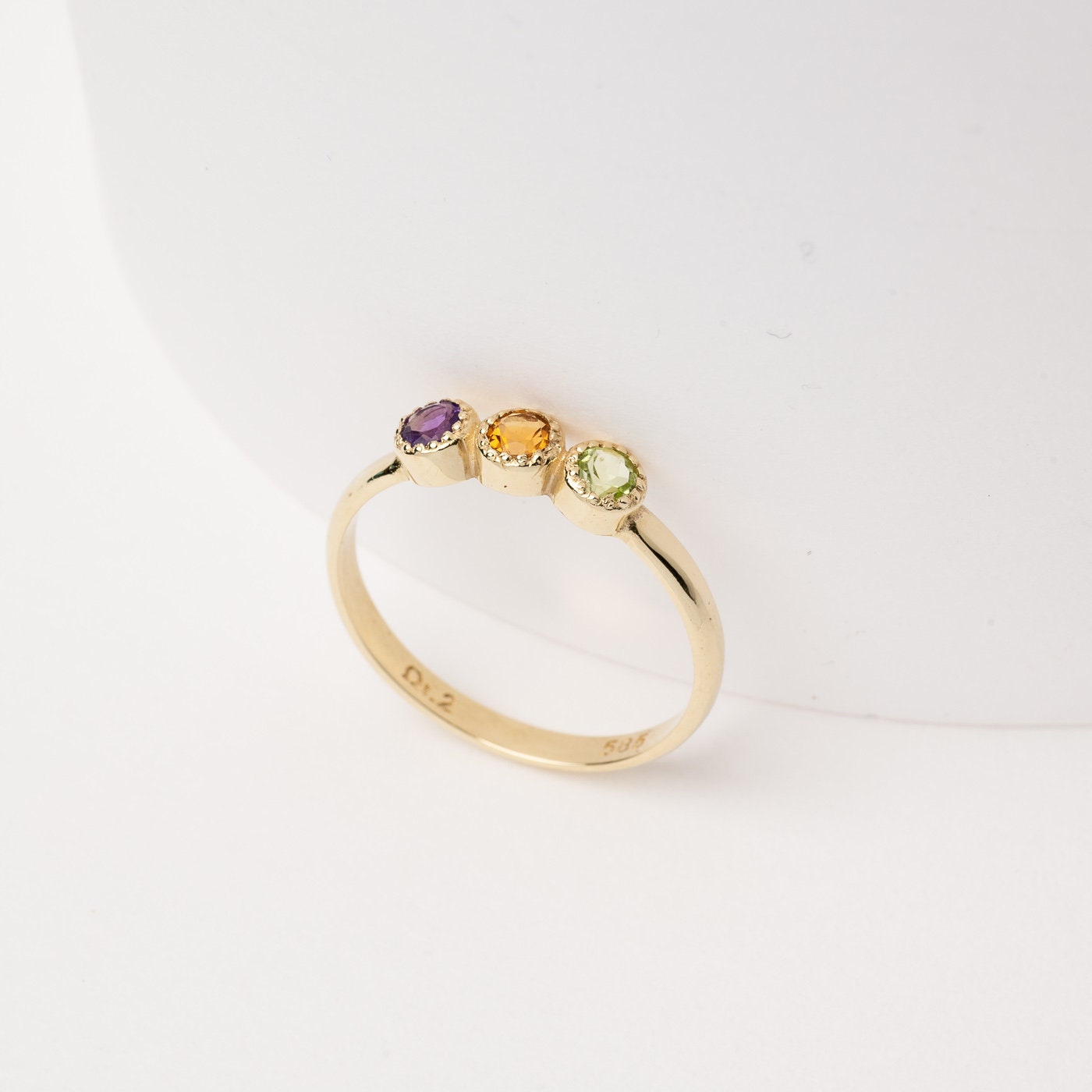 A handmade ring featuring three birthstones set in 14k solid gold with a prong setting.