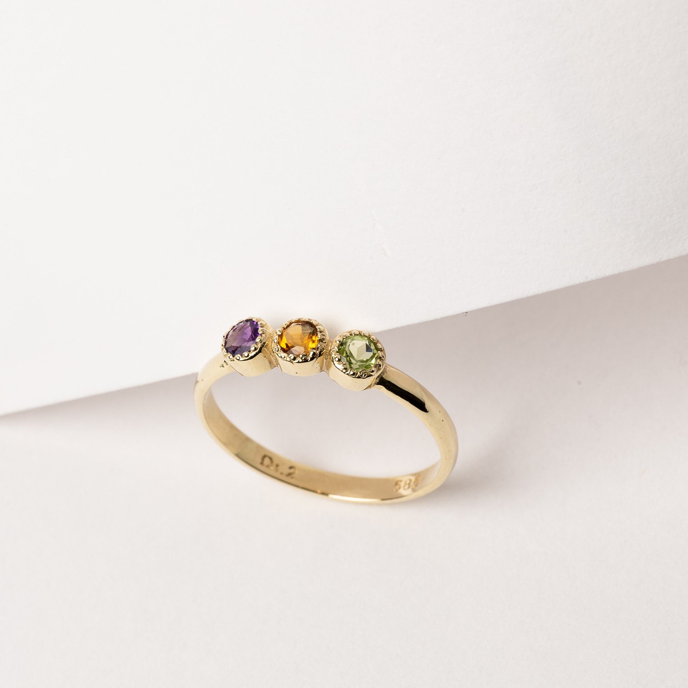 A handmade ring featuring three birthstones set in 14k solid gold with a prong setting.