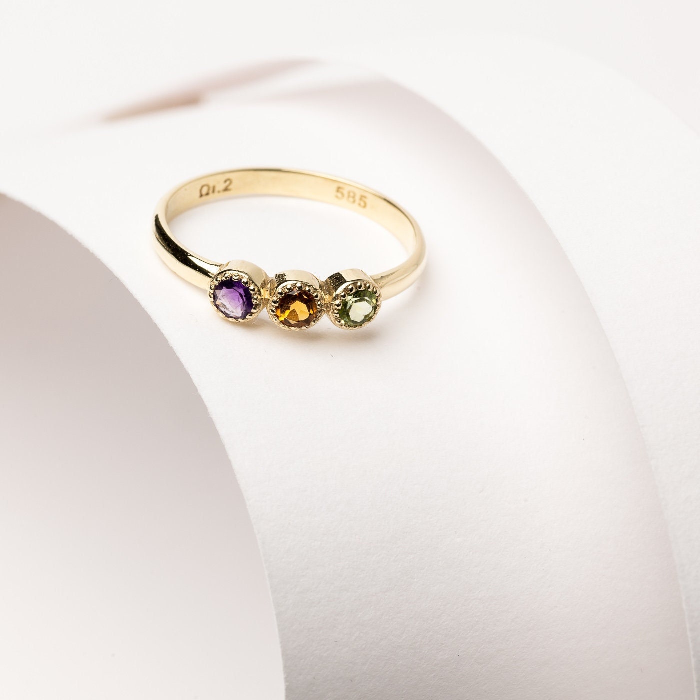 A handmade ring featuring three birthstones set in 14k solid gold with a prong setting.