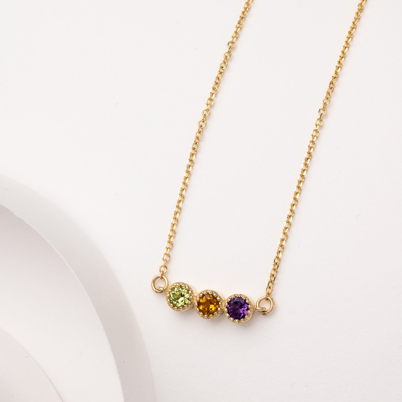 Handcrafted birthstone necklace in 14k gold, featuring three stones in a prong setting.