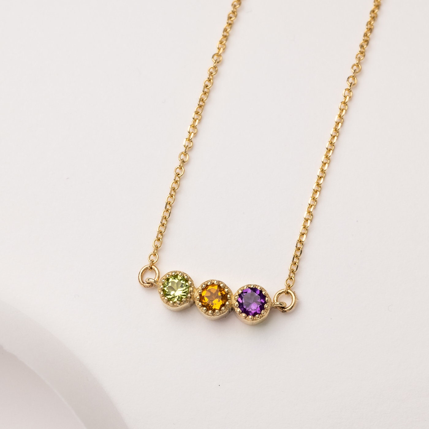 Handcrafted birthstone necklace in 14k gold, featuring three stones in a prong setting.