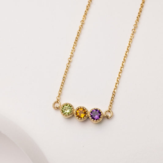 Handcrafted birthstone necklace in 14k gold, featuring three stones in a prong setting.