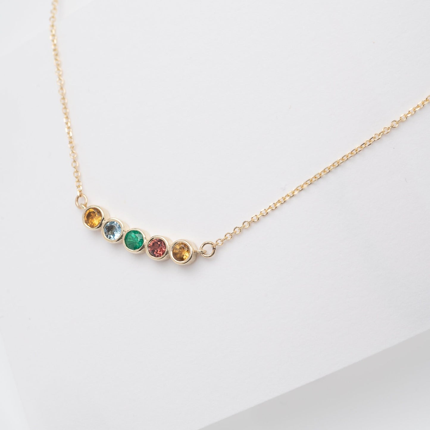 A 14k gold necklace for women, featuring five family birthstones.