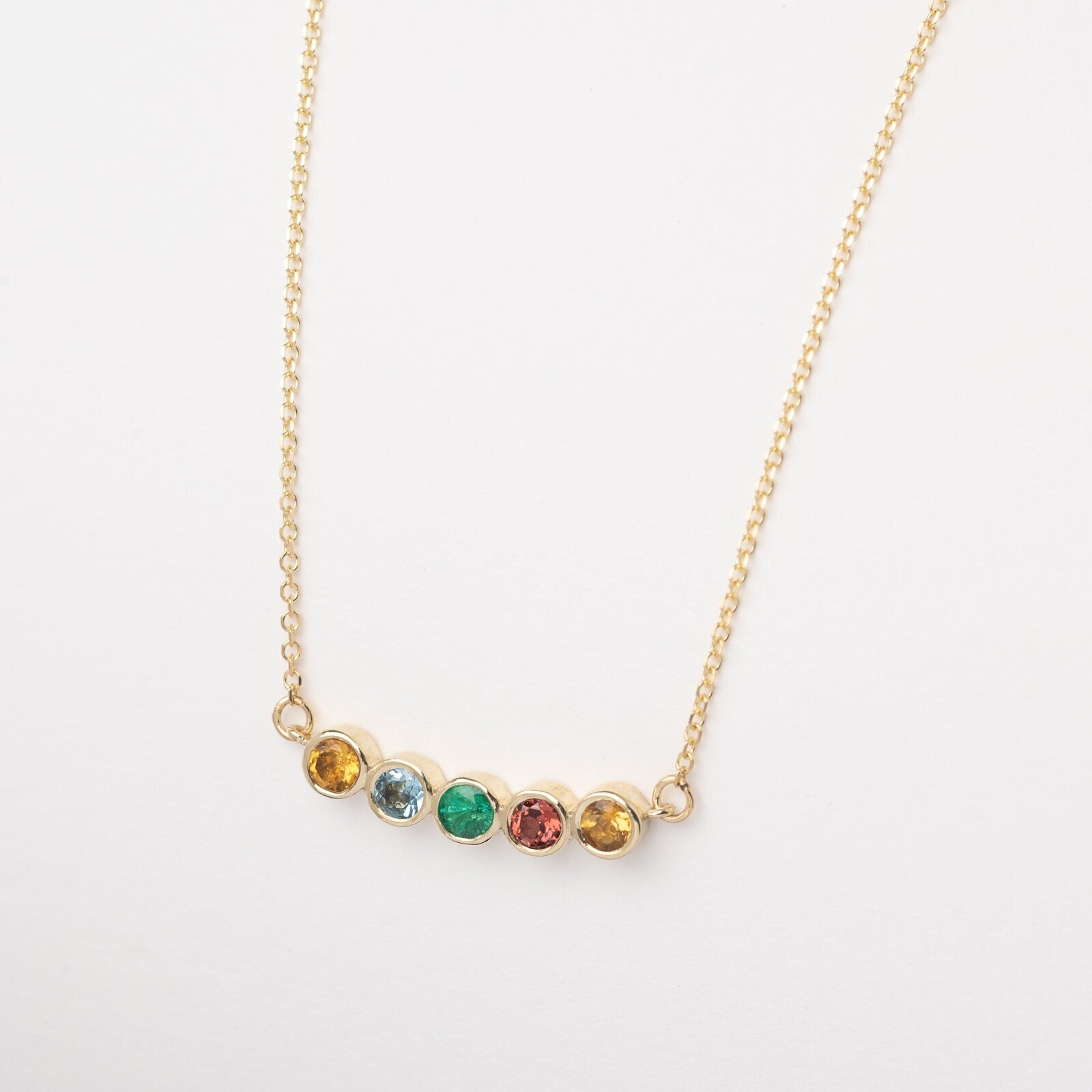 A 14k gold necklace for women, featuring five family birthstones.