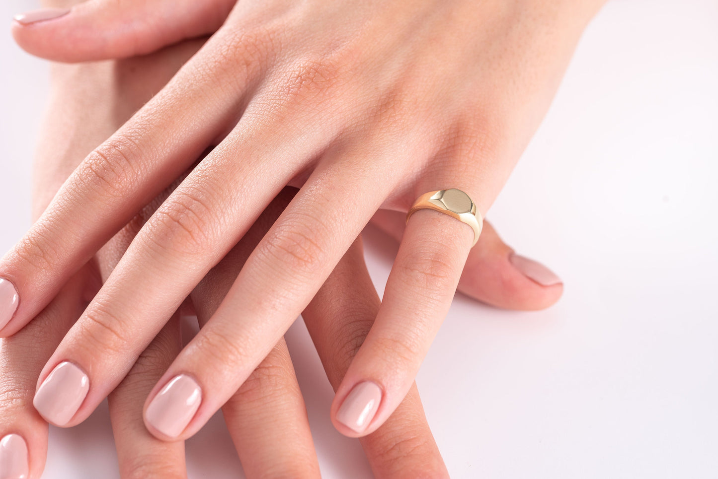 A model wears a minimalist personalized signet ring crafted in 14K gold on their pinky finger.