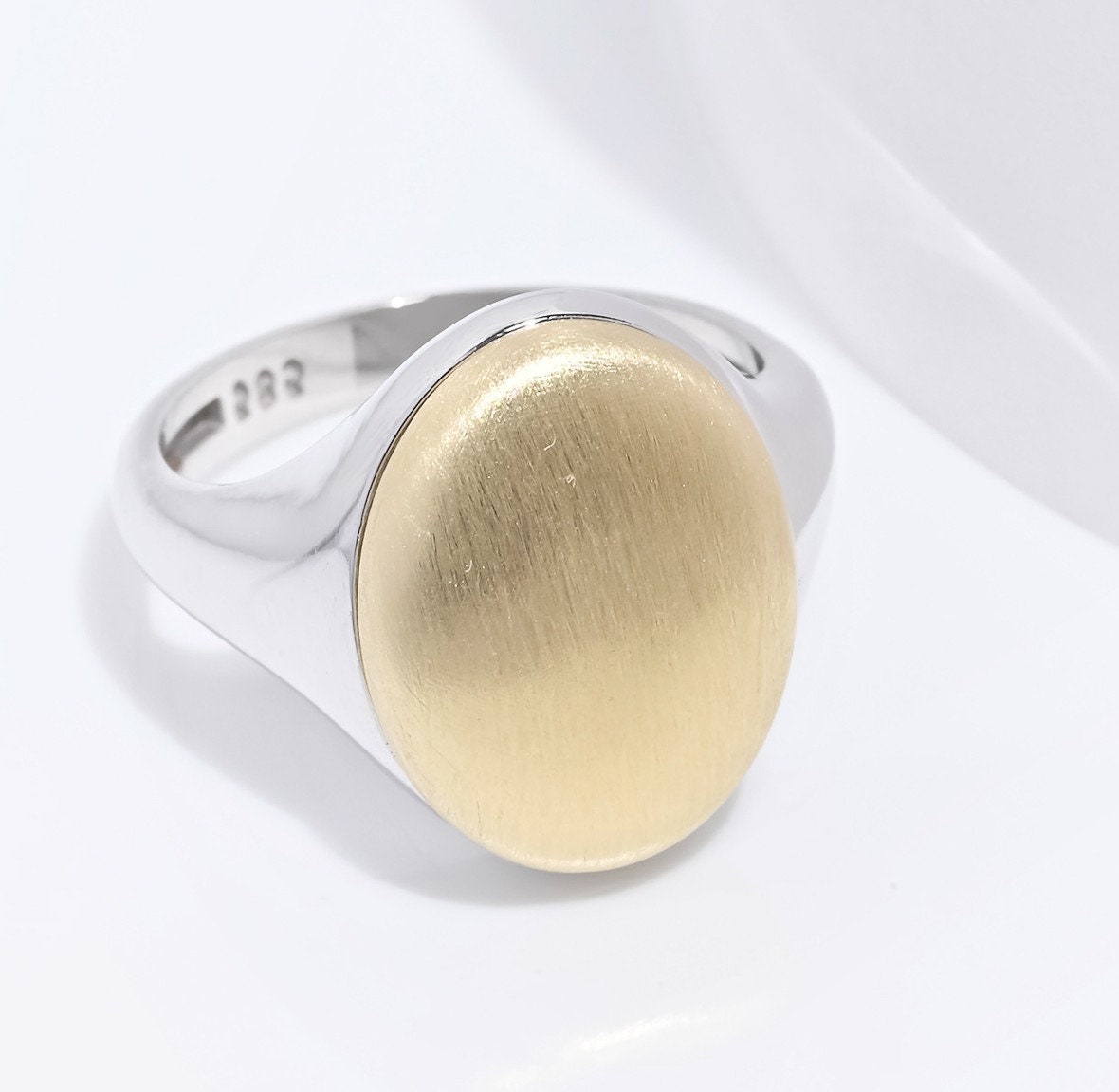 An oval personalized signet ring for women in 14k gold, with the top part engravable.