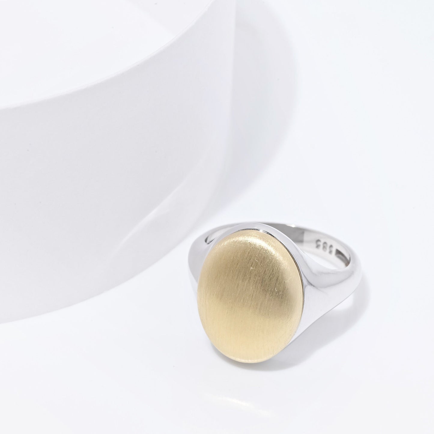 An oval personalized signet ring for women in 14k gold, with the top part engravable.