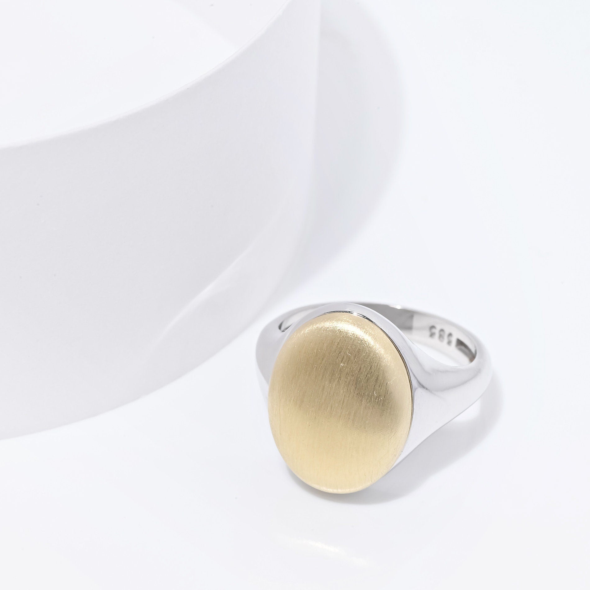 An oval personalized signet ring for women in 14k gold, with the top part engravable.