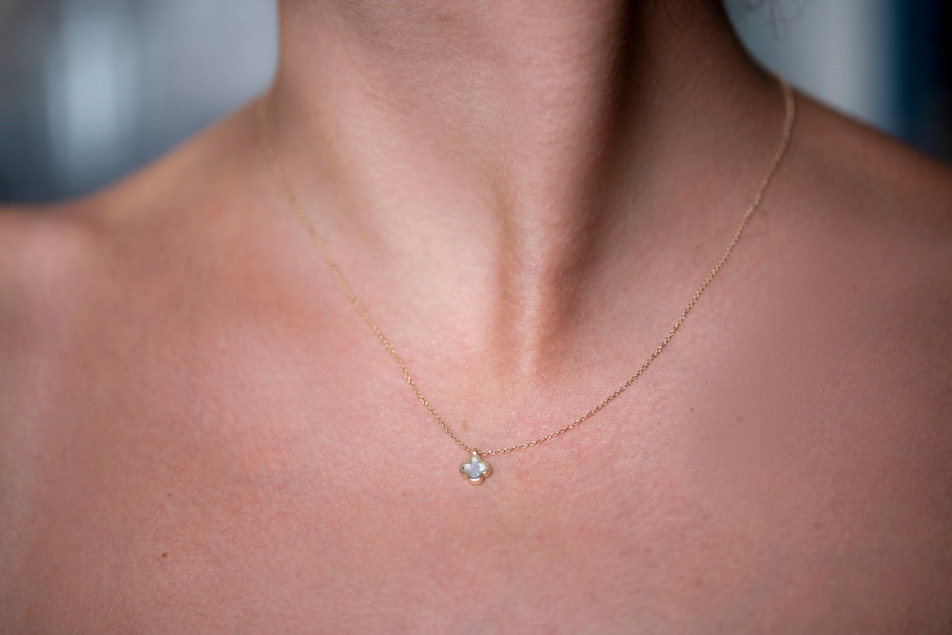 A 14k gold necklace for women, adorned with a clover-shaped mother of pearl motif.