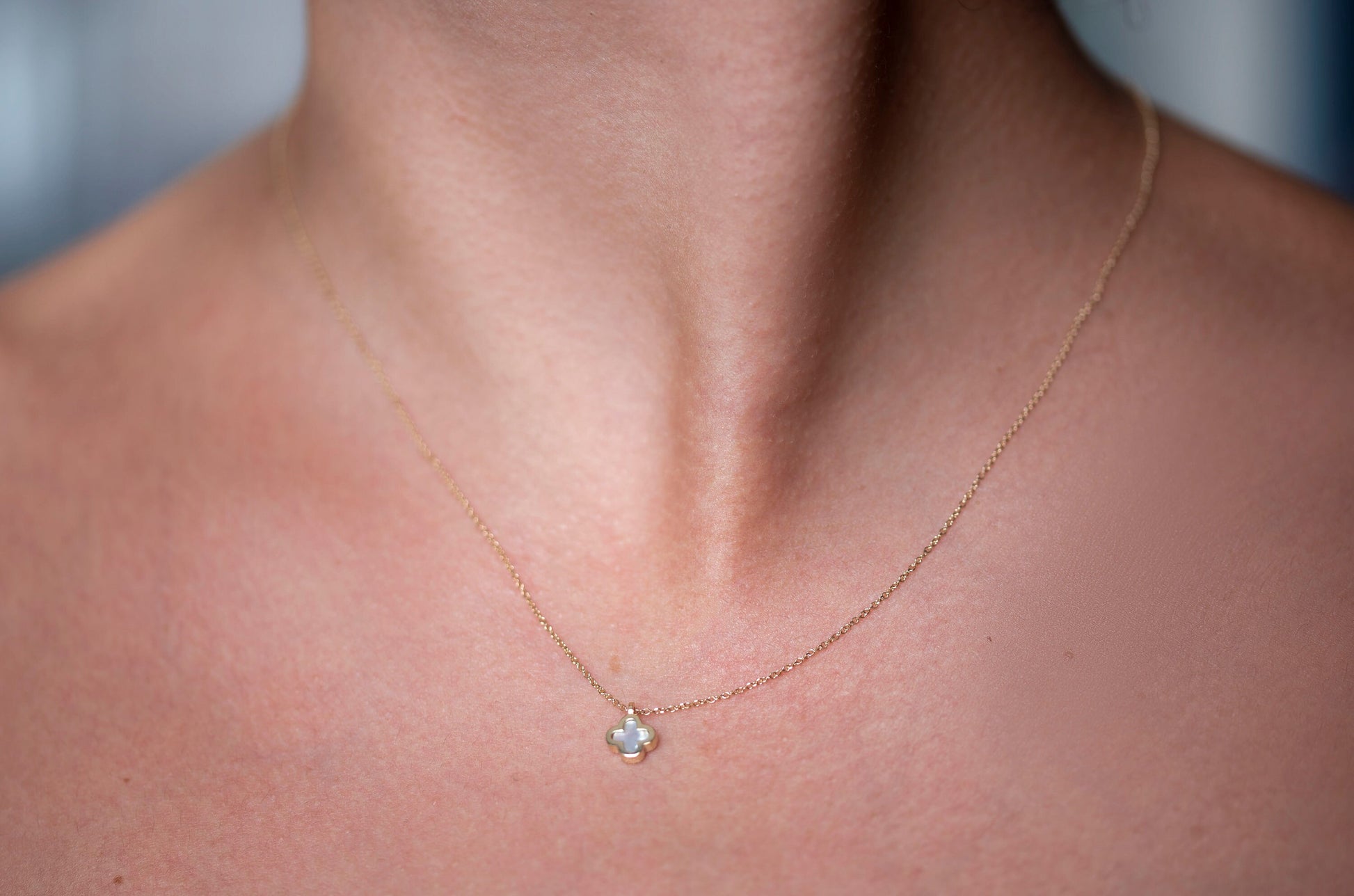 A 14k gold necklace for women, adorned with a clover-shaped mother of pearl motif.