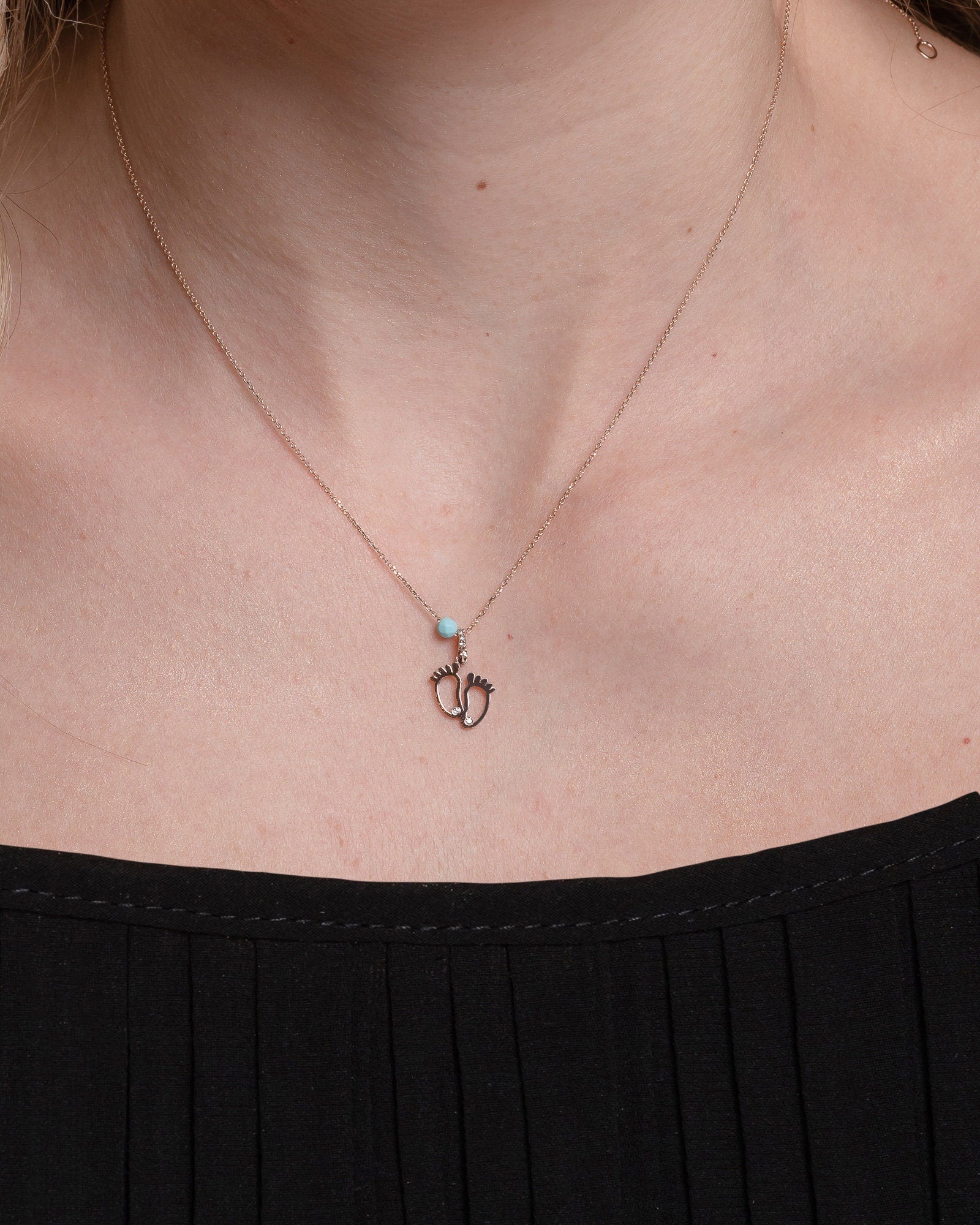 baby footprint necklace in 14k gold with cubic zirconia and turquoise stone worn by a model 