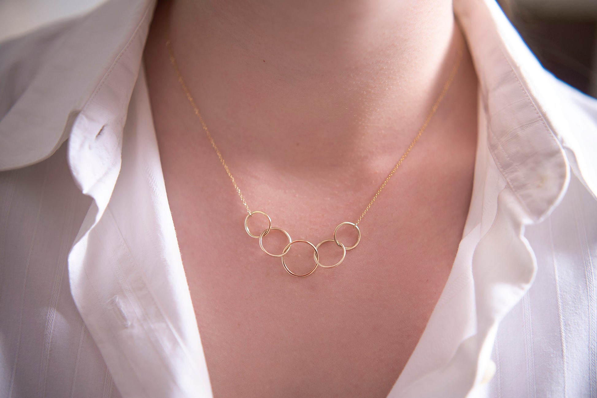 14k gold necklace with five interlocking circles for women worn by a model 