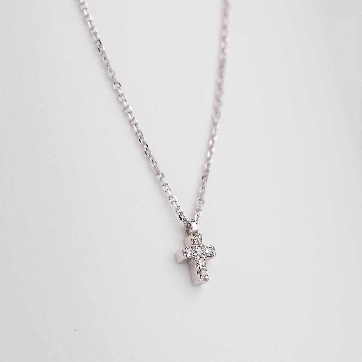 tiny diamond cross necklace in 14k white gold for women wron by a model 