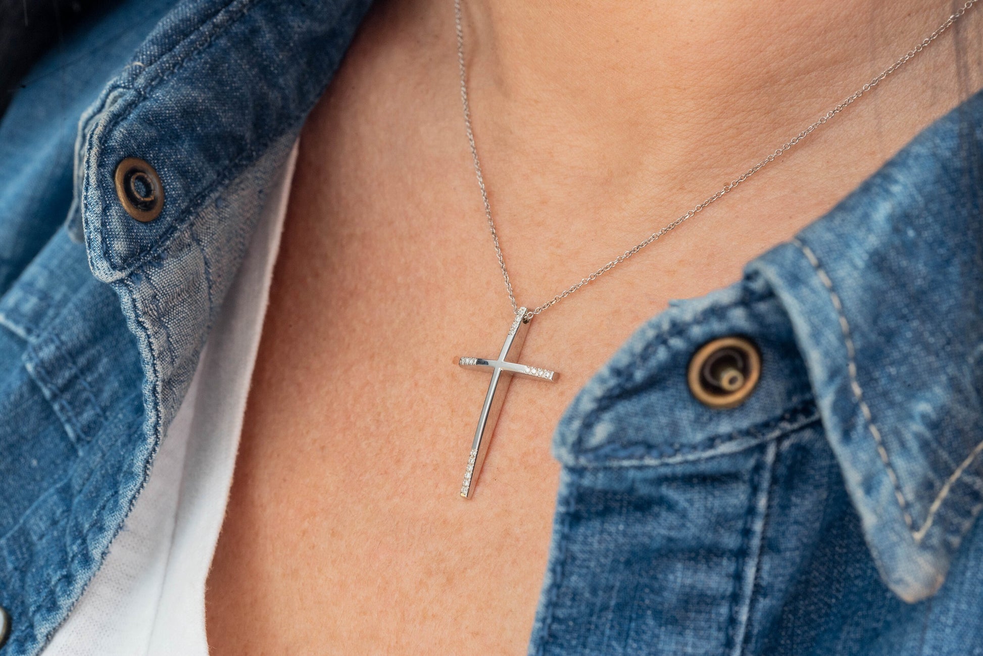 slim diamond cross necklace in 18k white gold for women worn by a model 