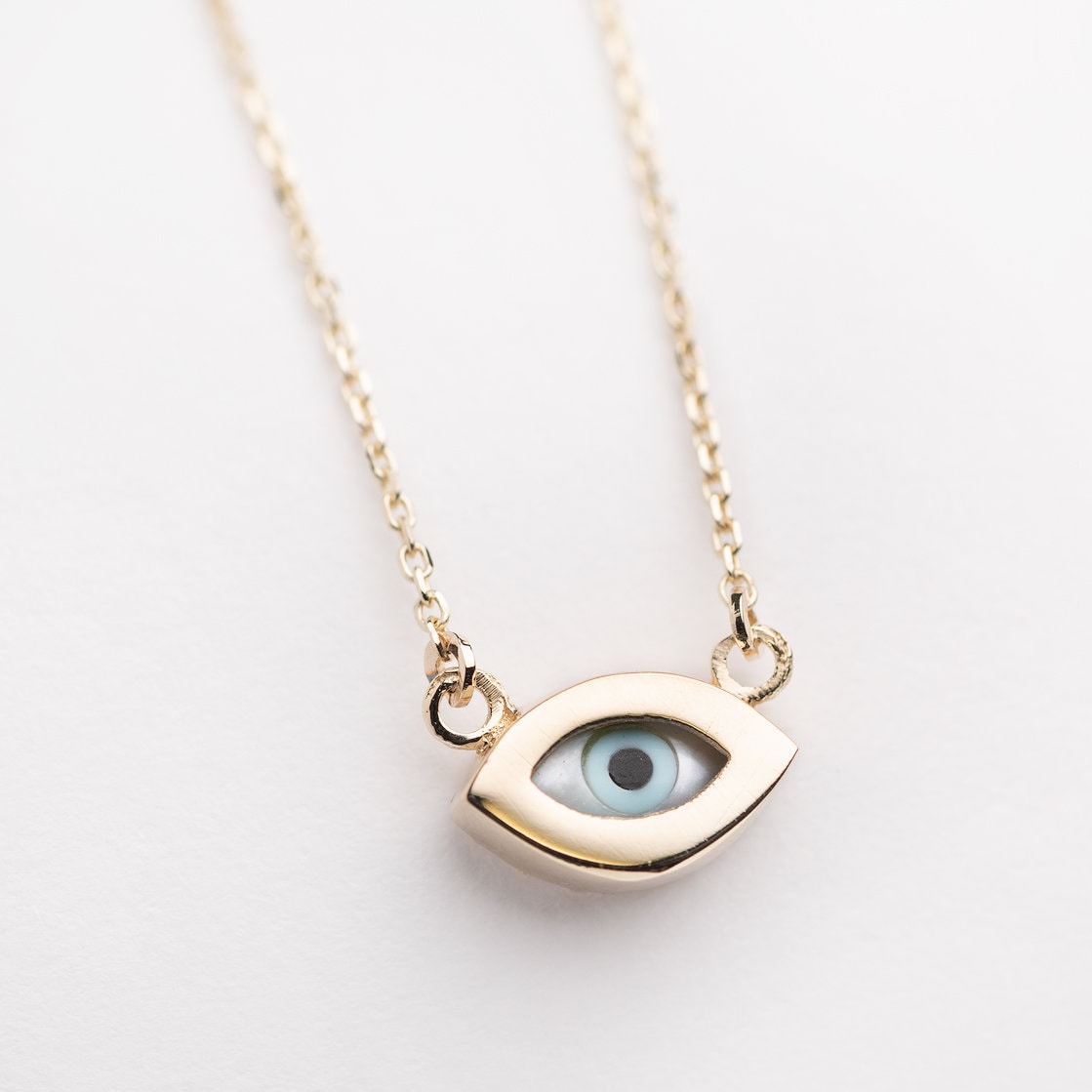 An oval-shaped evil eye necklace featuring mother of pearl, set in 14k gold for women.