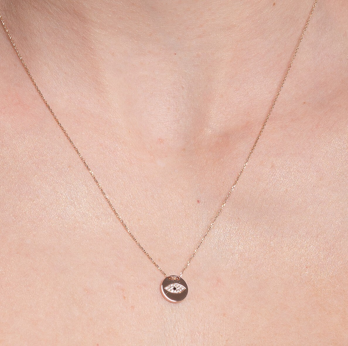 Pavé evil eye necklace in 14k yellow gold for women worn by a model 