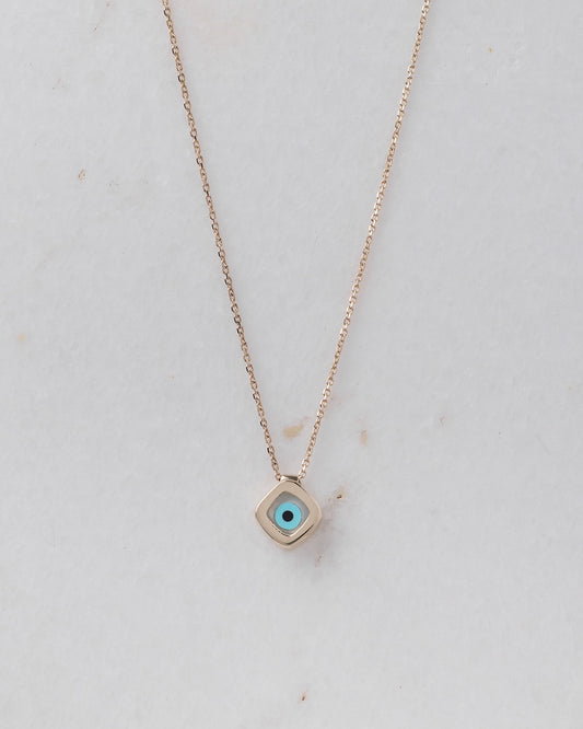 A mother-of-pearl evil eye necklace in 14k gold, fashioned in a rhombus shape.