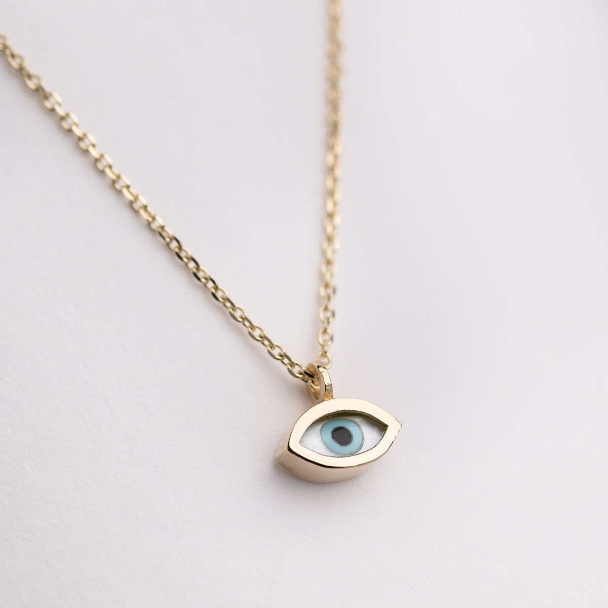 Tiny mother-of-pearl evil eye necklace in 14k gold for women.