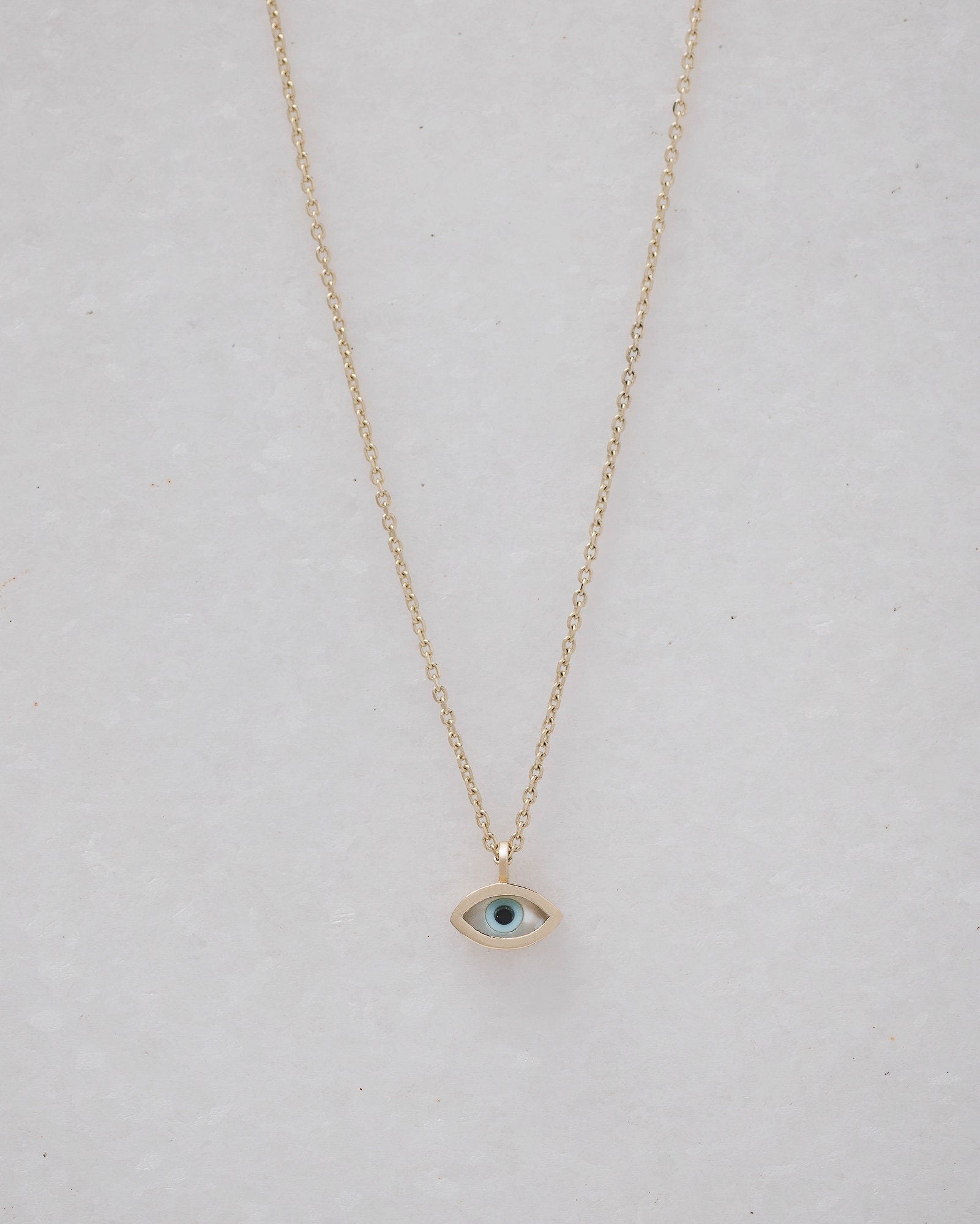 Tiny mother-of-pearl evil eye necklace in 14k gold for women.