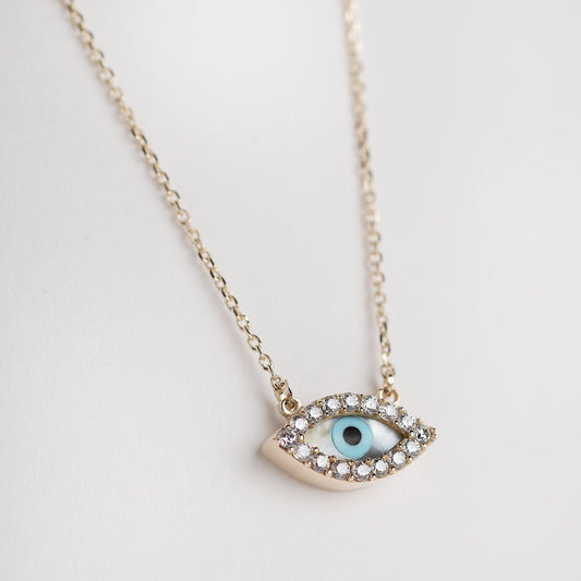 An oval-shaped mother of pearl evil eye necklace for women, crafted in 14k gold and adorned with cubic zirconia stones.