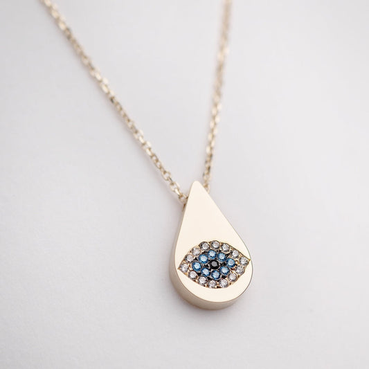 A drop-shaped evil eye necklace, encrusted with cubic zirconia stones and set in 14k gold.