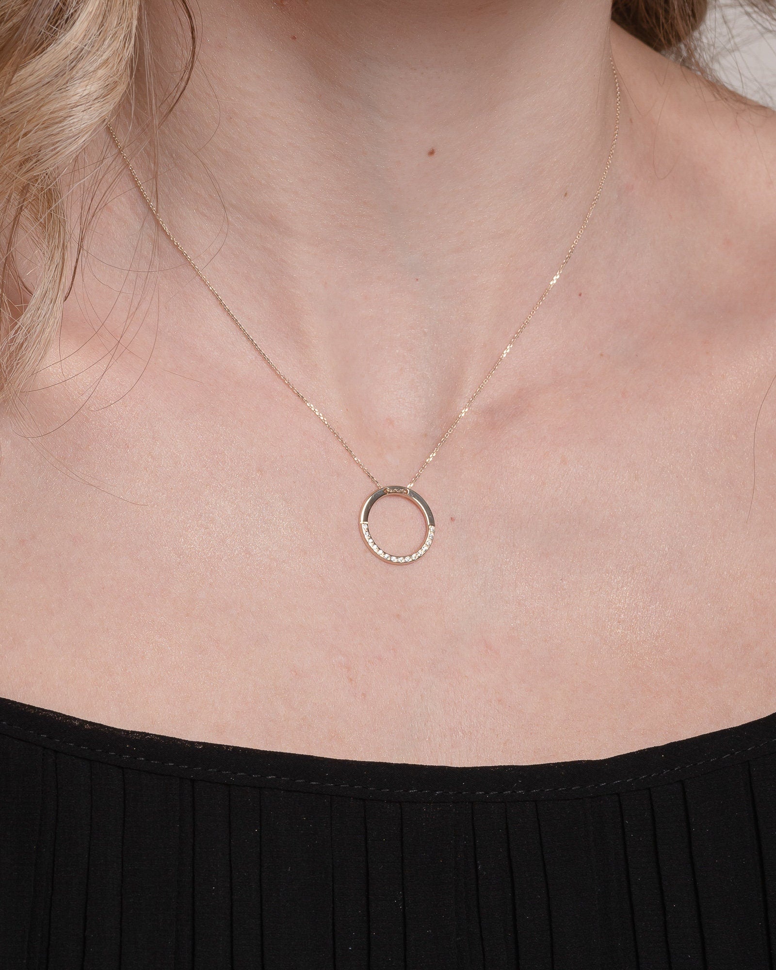 circle karma necklce in 14k gold half of the necklace is paved with cubic zirconia stones worn by a model 