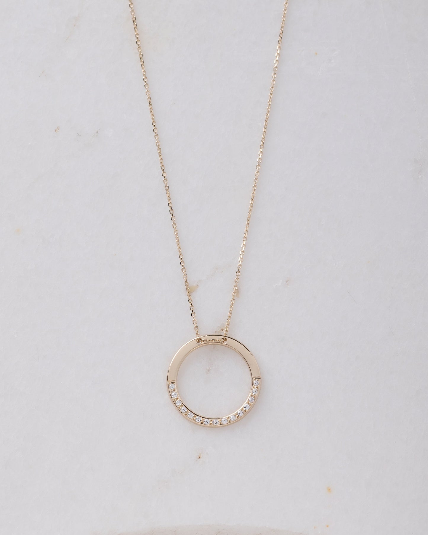 circle karma necklce in 14k gold half of the necklace is paved with cubic zirconia stones