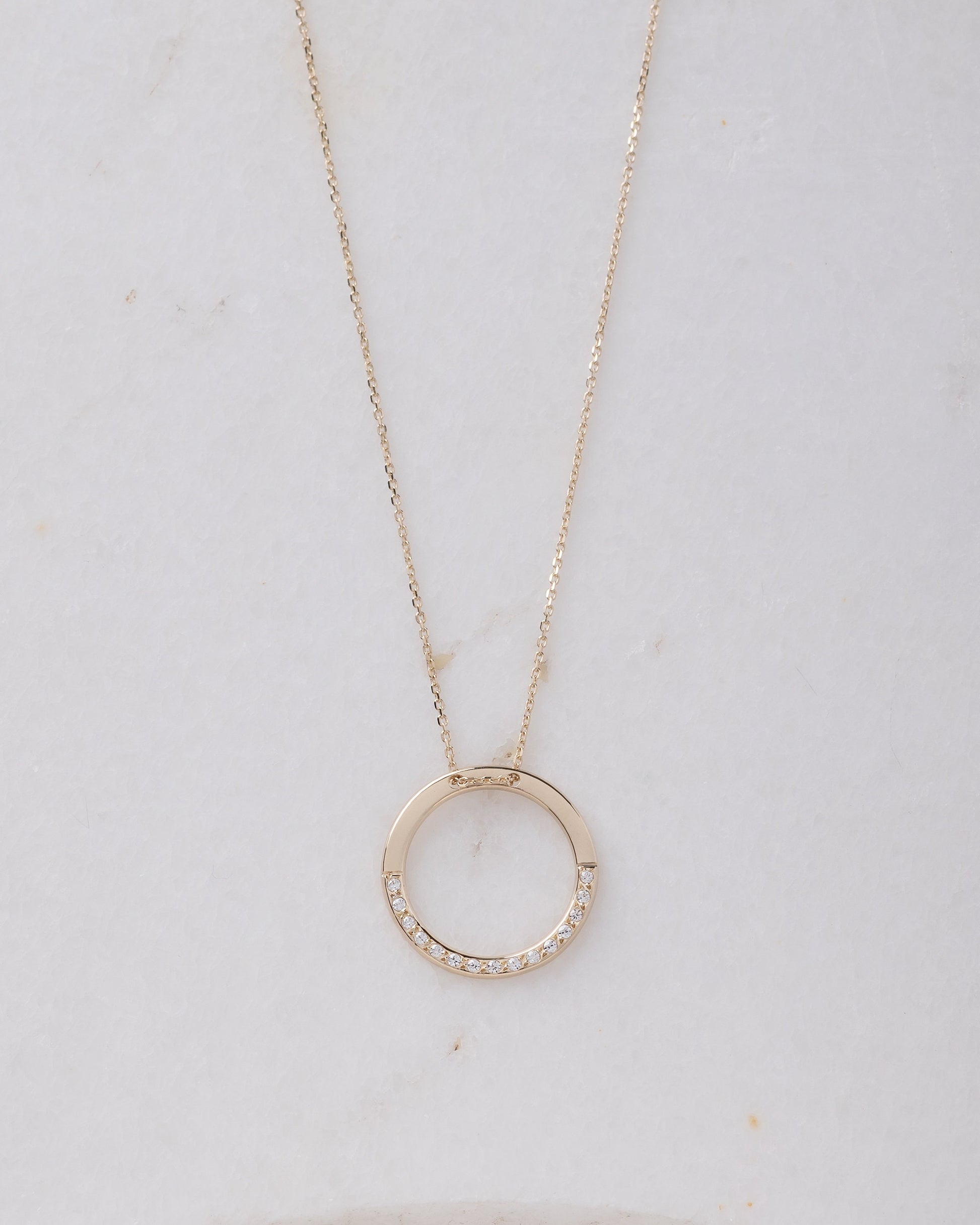 circle karma necklce in 14k gold half of the necklace is paved with cubic zirconia stones