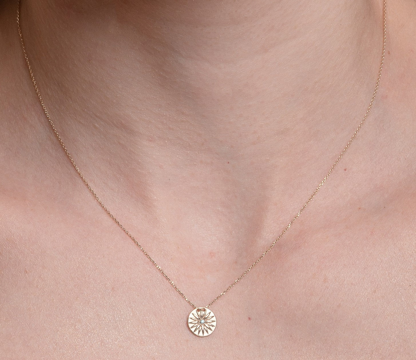 14k gold vergina star necklace with a blue cubic zirconia stone worn by a model 