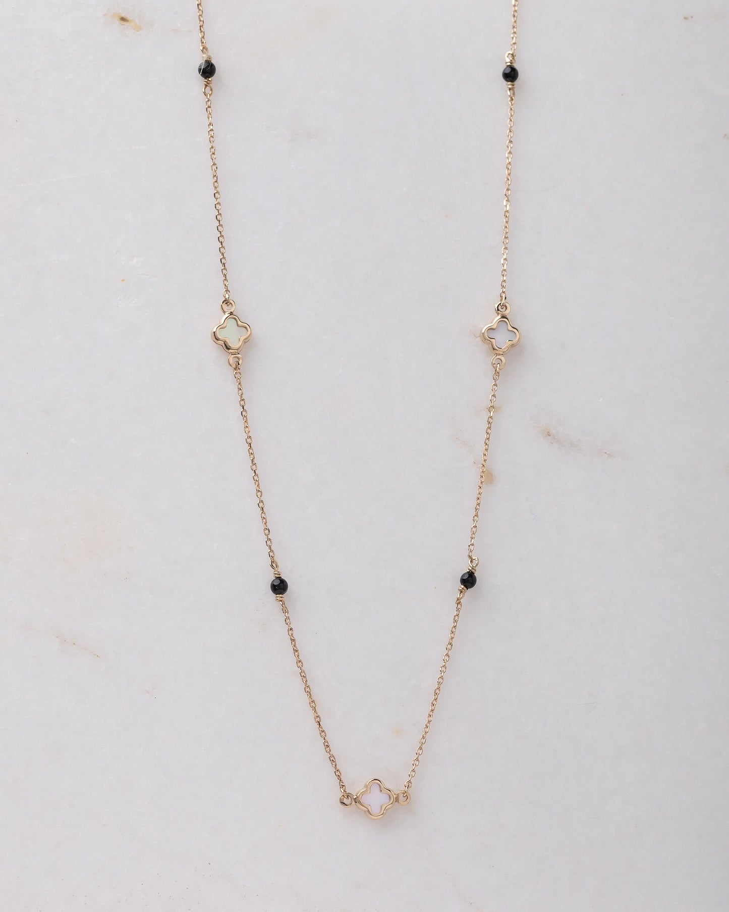 Mother-of-pearl clover necklace with onyx beads in 14k gold.