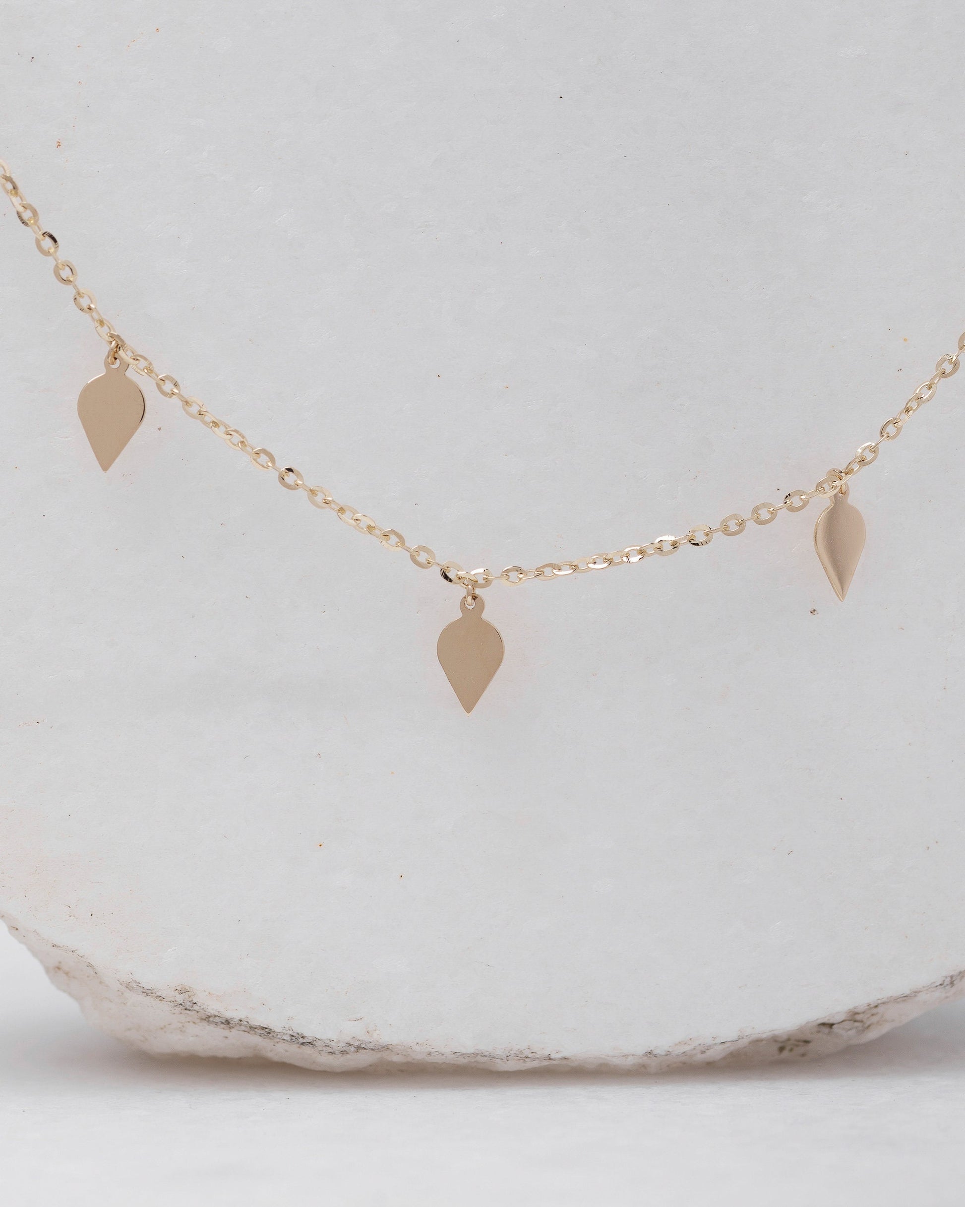 A station necklace featuring seven leaves crafted in 14k yellow gold for women.