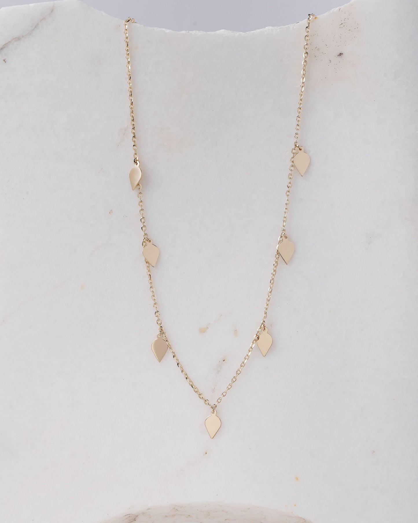 A station necklace featuring seven leaves crafted in 14k yellow gold for women.