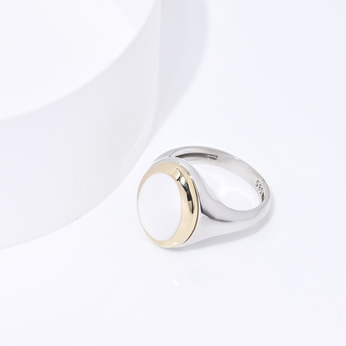 A women's signet ring in 14k gold with white enamel and a two-tone design.