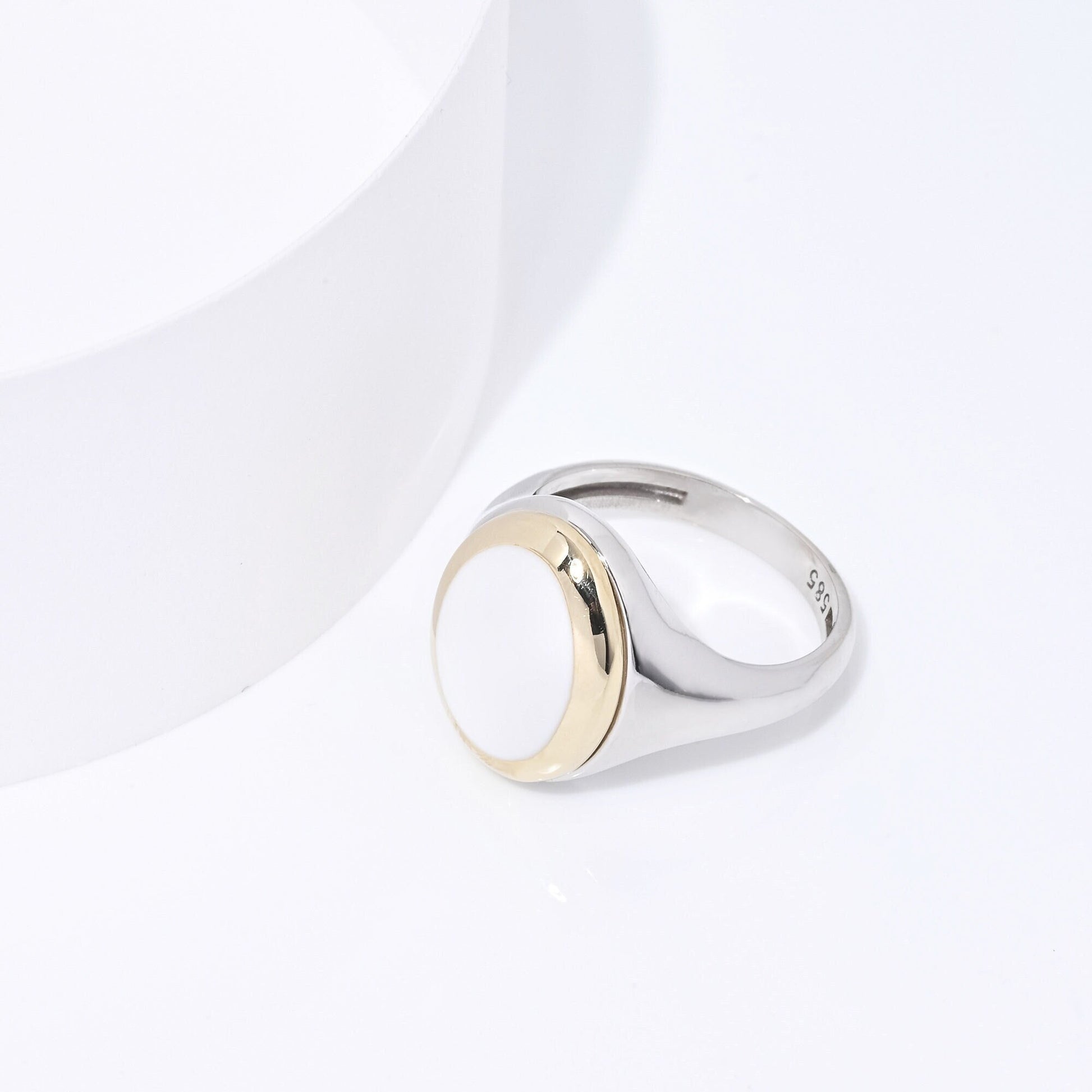 A women's signet ring in 14k gold with white enamel and a two-tone design.