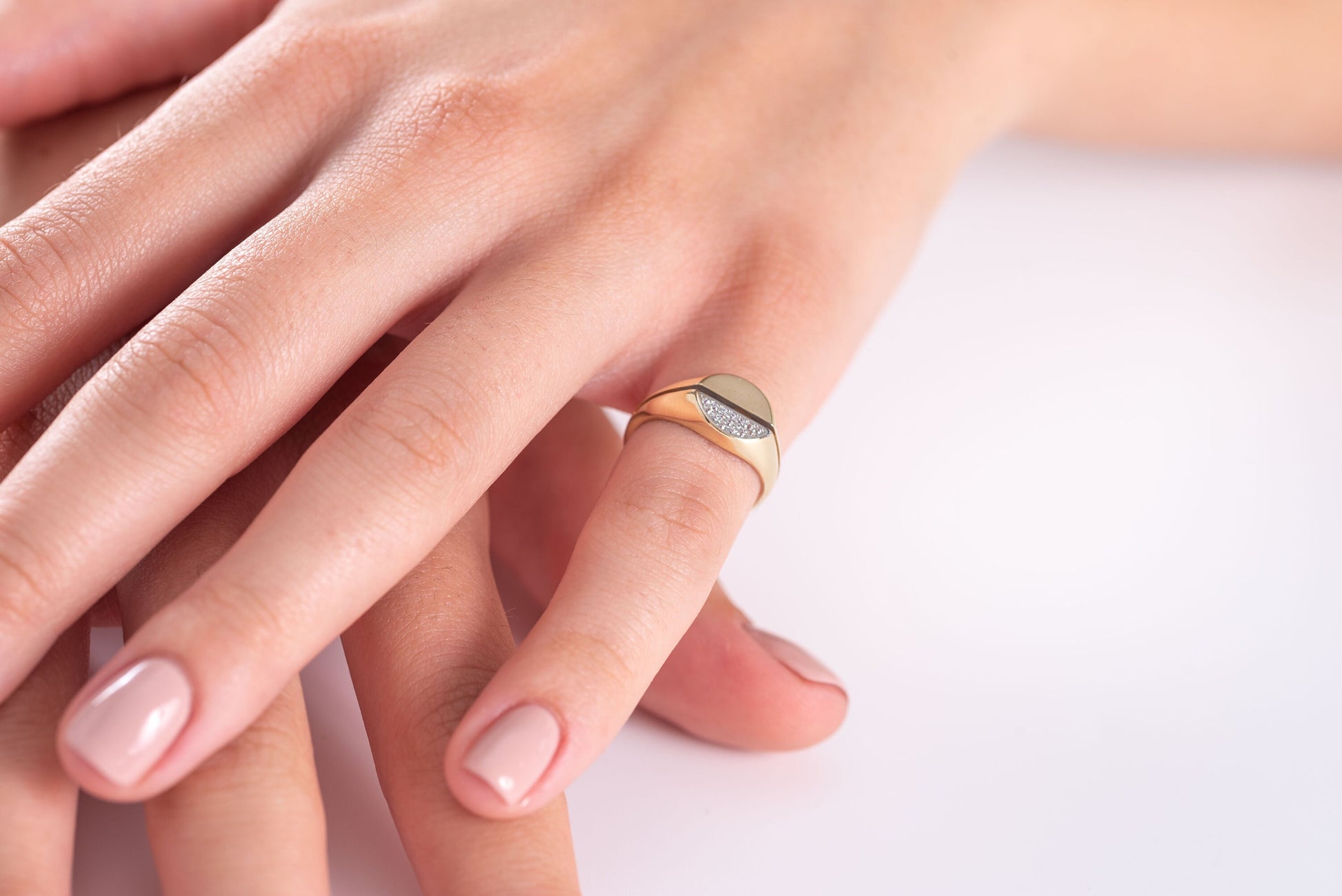 A round signet ring crafted in 14k gold, with half of the top part encrusted with white cubic zirconia stones.