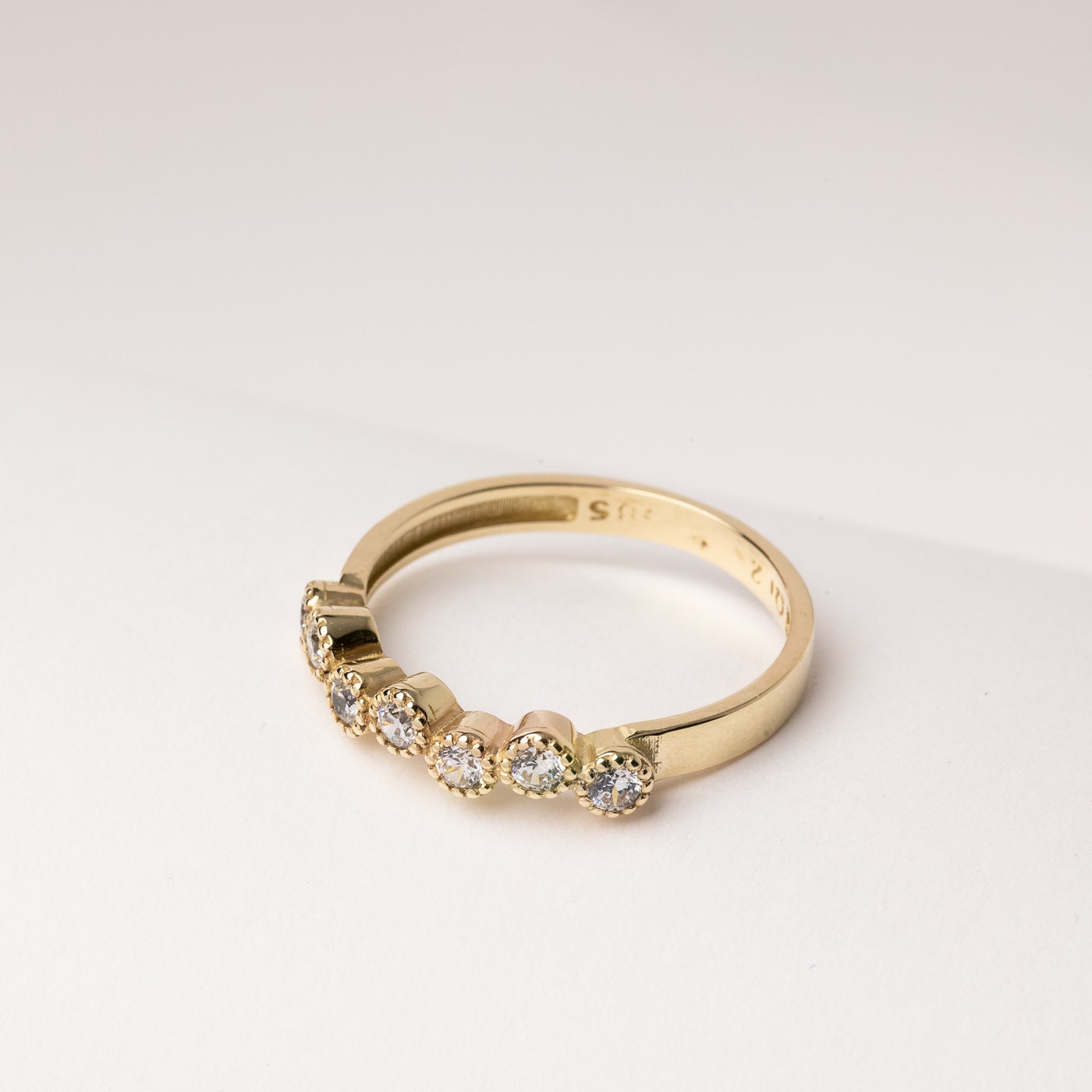 A half-eternity asymmetrical band crafted in 14k solid gold, adorned with white cubic zirconia stones.