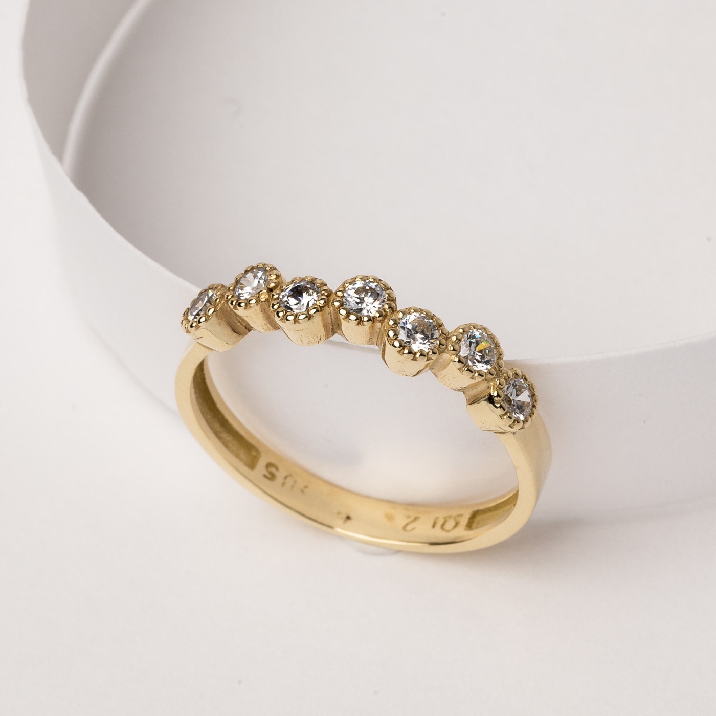 A half-eternity asymmetrical band crafted in 14k solid gold, adorned with white cubic zirconia stones.